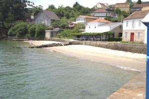 Blick auf einen Strand mit Häusern am Wasser in der Unterkunft Casita con terreno a 10 minutos del centro de Vigo in Moaña