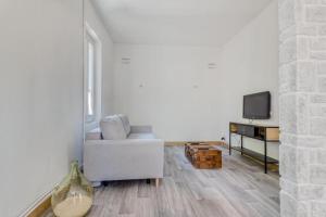 a living room with a couch and a tv at L'Ardeche en Provence avec jardin ombragé in Pont-Saint-Esprit