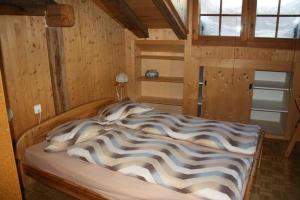un grande letto in una camera con pareti in legno di Plazzetta 23 a Sent