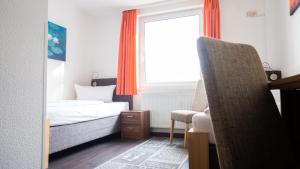 ein Schlafzimmer mit einem Bett, einem Fenster und einem Stuhl in der Unterkunft Aalreuse in Rostock