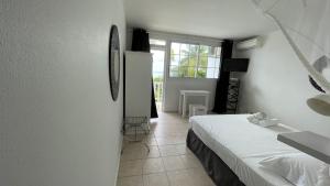 a small bedroom with a bed and a window at Le M Hotel Marie Galante in Beauregard