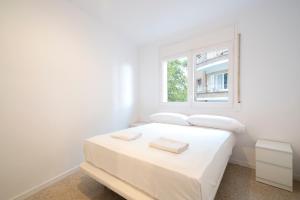 a white bedroom with a white bed and a window at Homenfun Barcelona Park Güell in Barcelona