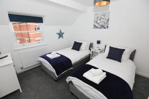 1 dormitorio con 2 camas y ventana en Strand House Flat 2 Free Parking, by RentMyHouse en Exmouth