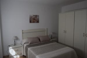 een witte slaapkamer met een bed en een kast bij CASA DEL VIDRIO in Castril