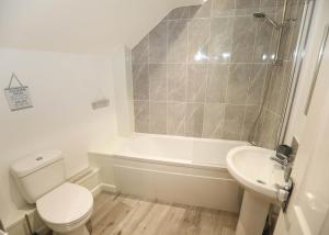 a bathroom with a toilet and a tub and a sink at Strand House Flat 2 Free Parking, by RentMyHouse in Exmouth