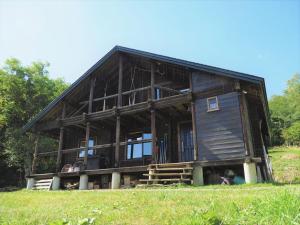 uma grande casa de madeira situada no topo de um campo em Minanonno Play Village em Yoichi