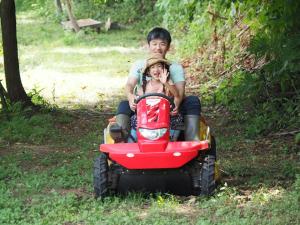 un hombre y una mujer montados en un vehículo de cuatro ruedas en Minanonno Play Village, en Yoichi