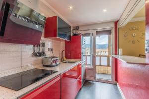 a kitchen with red cabinets and a large window at Bilbao Airport by Aston Rentals in Derio