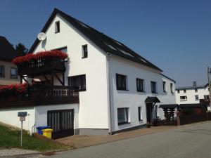 a white house with a black roof and a balcony at Ferienwohnung Auris in Cranzahl