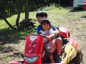 Chłopiec i dziewczynka jeżdżący na motocyklu w obiekcie Minanonno Play Village w mieście Yoichi