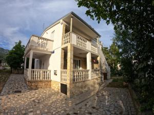 a white house with a balcony on a street at Apartments Lana - 30 m from the sea in Seline