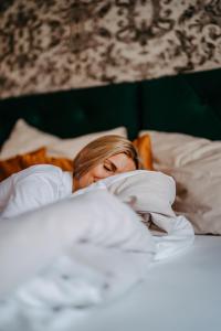 a woman laying in bed under a blanket at Hotel Palais26 in Villach