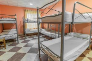 a room with three bunk beds and a checkered floor at Albergue Rojo Plata in Torremegía