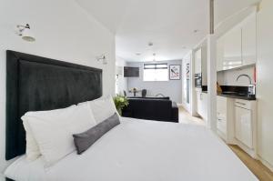 a bedroom with a large white bed with a black headboard at Crane Court by City2Stay in London