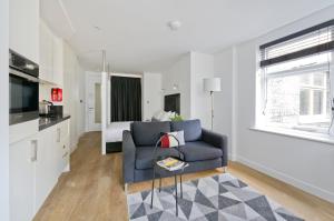 a living room with a blue couch and a bed at Crane Court by City2Stay in London