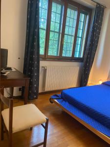 een slaapkamer met een blauw bed, een bureau en een raam bij Cascina Cavalli Astino in Bergamo