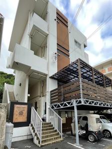 un bâtiment avec des escaliers et un camion garé devant. dans l'établissement i home Tsubogawa / Vacation STAY 53026, à Naha