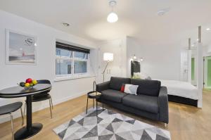 a living room with a couch and a bed at Crane Court by City2Stay in London