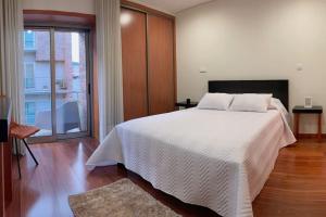 a bedroom with a white bed and a large window at Casa das Estrelas in Braga