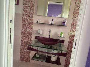 y baño con lavabo de cristal y espejo. en La Bomboniera di Marco, en Fabro