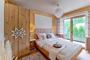 ein Schlafzimmer mit einem Bett mit einer Holzwand in der Unterkunft Rezydencja Górska Odkryj Zakopane in Zakopane