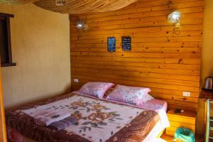1 dormitorio con 1 cama con pared de madera en Vila Ecológica Pousada Holística en Cambara do Sul
