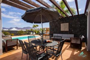 馬西尼古蒂的住宿－Captivating 2-Bed Villa in Playa Blanca，庭院设有带遮阳伞的桌子和游泳池。