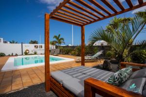 a patio with a pergola and a swimming pool at Captivating 2-Bed Villa in Playa Blanca in Playa Blanca