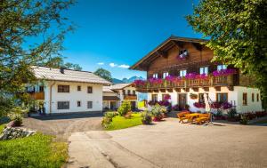 ein Haus mit einem Balkon und Bänken davor in der Unterkunft Lindbichlhof Urlaub am Bio Bauernhof in St. Johann im Pongau