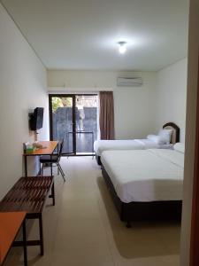 Habitación de hotel con 2 camas, mesa y escritorio en Hotel Larensia, en Labuan Bajo