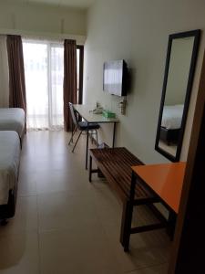 Habitación con cama, mesa y espejo. en Hotel Larensia, en Labuan Bajo
