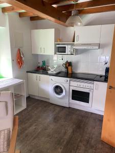 a kitchen with white cabinets and a washing machine at El Descanso Lastres in Colunga +8 photos