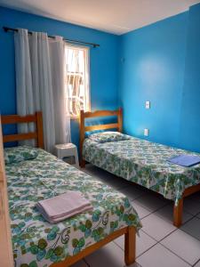 two beds in a room with blue walls at Apartamento Mobiliado Vila Iracema in Fortaleza