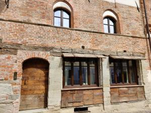 an old brick building with doors and windows at Domus Acaja in Pinerolo