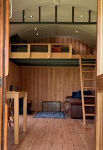 a room with a bunk bed and a table at Shepherds Hut in a private meadow with sea views in Hartland