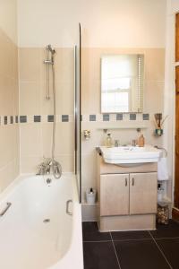 a bathroom with a tub and a sink and a mirror at Hampstead 19th Century Village Cottage in London