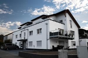 een wit gebouw met een auto geparkeerd op een parkeerplaats bij Panorama Suite 20 in Sinsheim