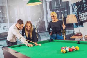 a group of people standing around a pool table at Mártoni Resort & Restaurant in Szigetszentmárton