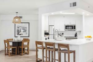 uma cozinha com armários brancos e uma mesa e cadeiras em Stunning Centrally Located Apartments at New River Cove in South Florida em Fort Lauderdale