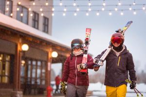 dos personas están sosteniendo sus esquís en una calle en Hotel Stoneham, en Stoneham