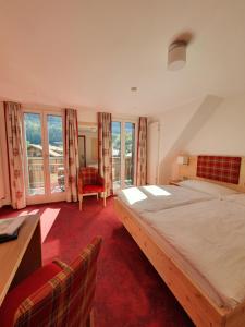 Schlafzimmer mit einem Bett, einem Schreibtisch und Fenstern in der Unterkunft Hotel Strandhotel in Iseltwald