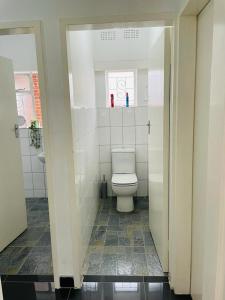 La salle de bains blanche est pourvue de toilettes et d'un lavabo. dans l'établissement Remarkable 2-Bed House in Bulawayo, à Bulawayo