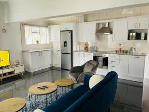 a kitchen with white cabinets and a blue couch and tables at Bulawayo Bradfield Retreat - 3 Bed House in Bulawayo