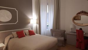 een slaapkamer met een bed met rode kussens en een spiegel bij Palazzo Gropallo Rooms in Genua