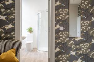 a bathroom with a shower and a wall with wallpaper at The Woodside in Doune