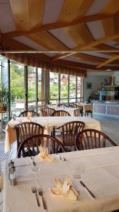 ein Esszimmer mit weißen Tischen, Stühlen und Fenstern in der Unterkunft Hotel Strandhotel in Iseltwald