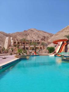 a pool of blue water with a water slide at Tobya Village Hotel in Taba