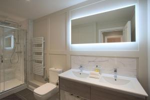 a bathroom with a sink and a toilet and a mirror at Harper Luxe Serviced Apartments Dunstable in Dunstable