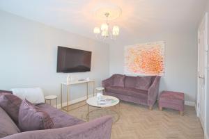 sala de estar con 2 sofás morados y TV en Harper Luxe Serviced Apartments Dunstable en Dunstable