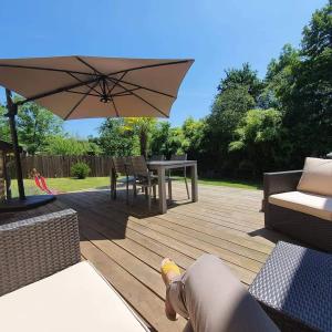 eine Holzterrasse mit einem Tisch und einem Sonnenschirm in der Unterkunft Gite correze spa jaccuzi massage in Saint-Germain-les-Vergnes